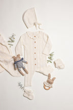 Little Box First Outfit da NOOK KIDS em tom cru, com conjunto de algodão orgânico e botinhas artesanais.