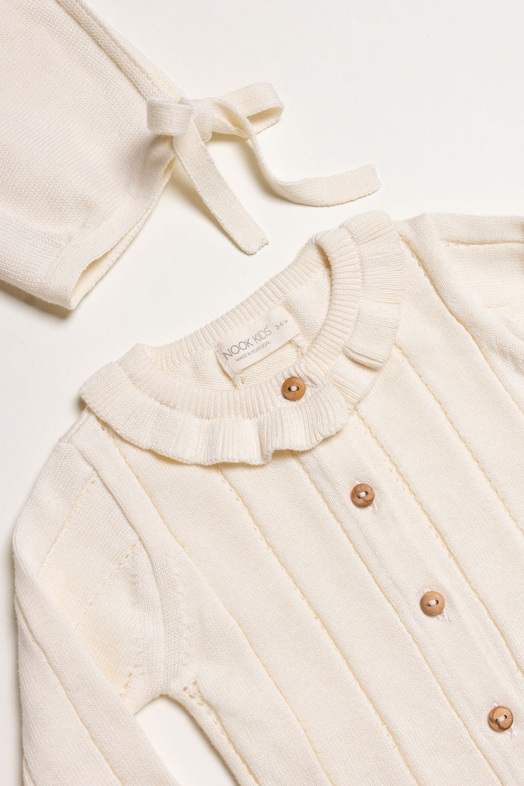 Little Box First Outfit da NOOK KIDS em tom cru, com conjunto de algodão orgânico e botinhas artesanais.
